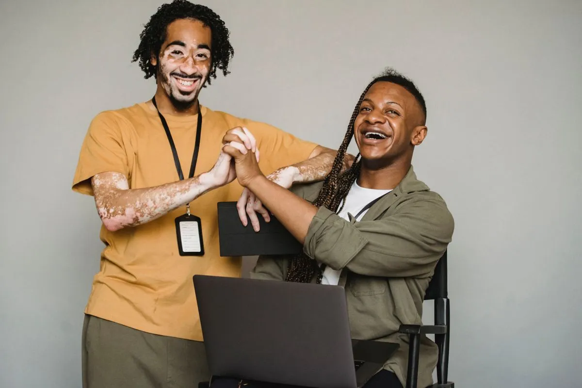 Two colleagues laughing together over a laptop